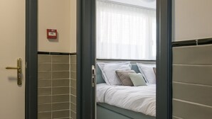 A hotel room with a bed, a door, and a tiled wall.