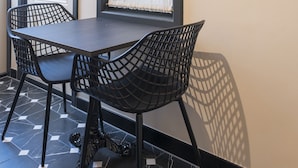 A dining area with a dark wooden table and black chairs, a potted plant on the wall, and a tiled floor.