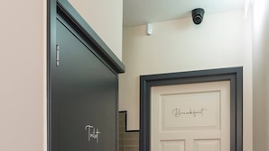 A hallway with a dark door labeled "Toilet" and a white door labeled "Breakfast."