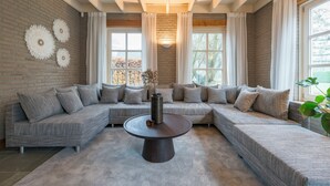 A modern living room with a sectional sofa, a round coffee table, and decorative wall art. - Spacious countryside stay near Boxtel with lake views, free parking and fast Wi-Fi. Quiet, comfortable and perfect for a relaxing getaway. (Boxtel)