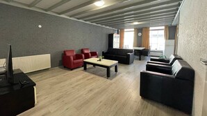 Un salon moderne avec une cheminée, des canapés rouges et noirs, une table basse et un coin repas avec une table et des chaises.