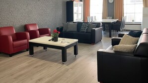Un salon moderne avec un mur en briques, un coin repas avec une table et des chaises, et une grande fenêtre avec des rideaux.