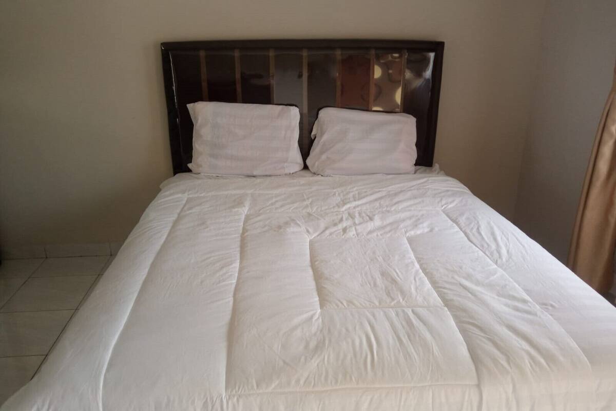 A bed with a dark headboard and white bedding, including two pillows and a duvet.