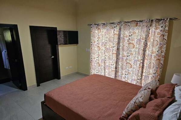 Une chambre à coucher avec un lit, une porte et un rideau.