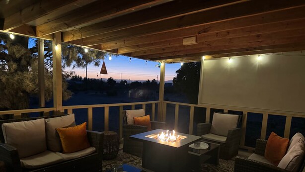 Een terras met rieten meubilair, een centraal vuurkorf en uitzicht op de avondhemel.