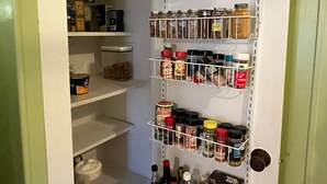 Een provisiekast met planken vol potten en bakken, een blik soep en een pak ontbijtgranen.
