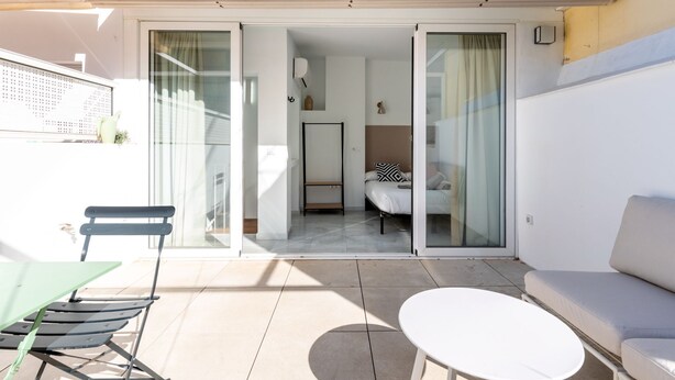 A modern outdoor patio with a sofa, a table, and a chair. - Dos de mayo - One Bedroom Apartment, Sleeps 3 (Sevilla)