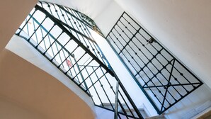 A spiral staircase with metal railings and a view of the outside through the windows. - Dos de mayo - One Bedroom Apartment, Sleeps 3 (Sevilla)