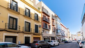 A narrow street lined with multi-story buildings, each with balconies and windows. - Dos de mayo - One Bedroom Apartment, Sleeps 3 (Sevilla)