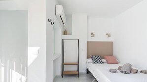 A modern bedroom with a bed, bedside lamps, and a hanging air conditioner. - Dos de mayo - One Bedroom Apartment, Sleeps 3 (Sevilla)