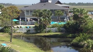 Uma casa com uma varanda grande, um lago e um quintal cercado.