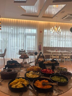 Een ontbijtbuffet met diverse gerechten en een zithoek met tafels en stoelen.
