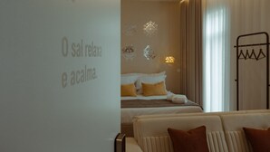 A hotel room with a bed, a sofa, and a wall with geometric light patterns. - Pedra de Sal Hostel & Suites (Rio Maior)