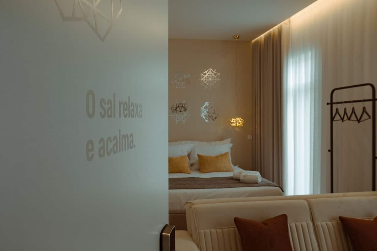 Ein Hotelzimmer mit einem Bett, einer Couch und einer Wand mit geometrischen Lichtmustern.