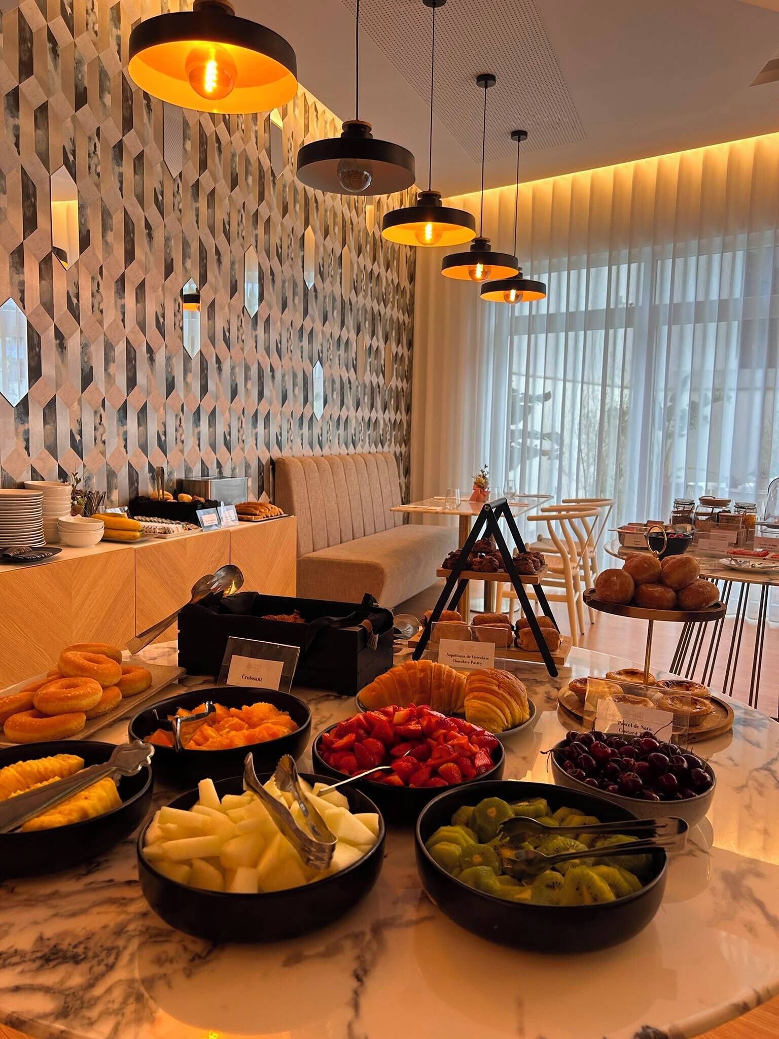 A breakfast buffet with various food items and a modern interior design.