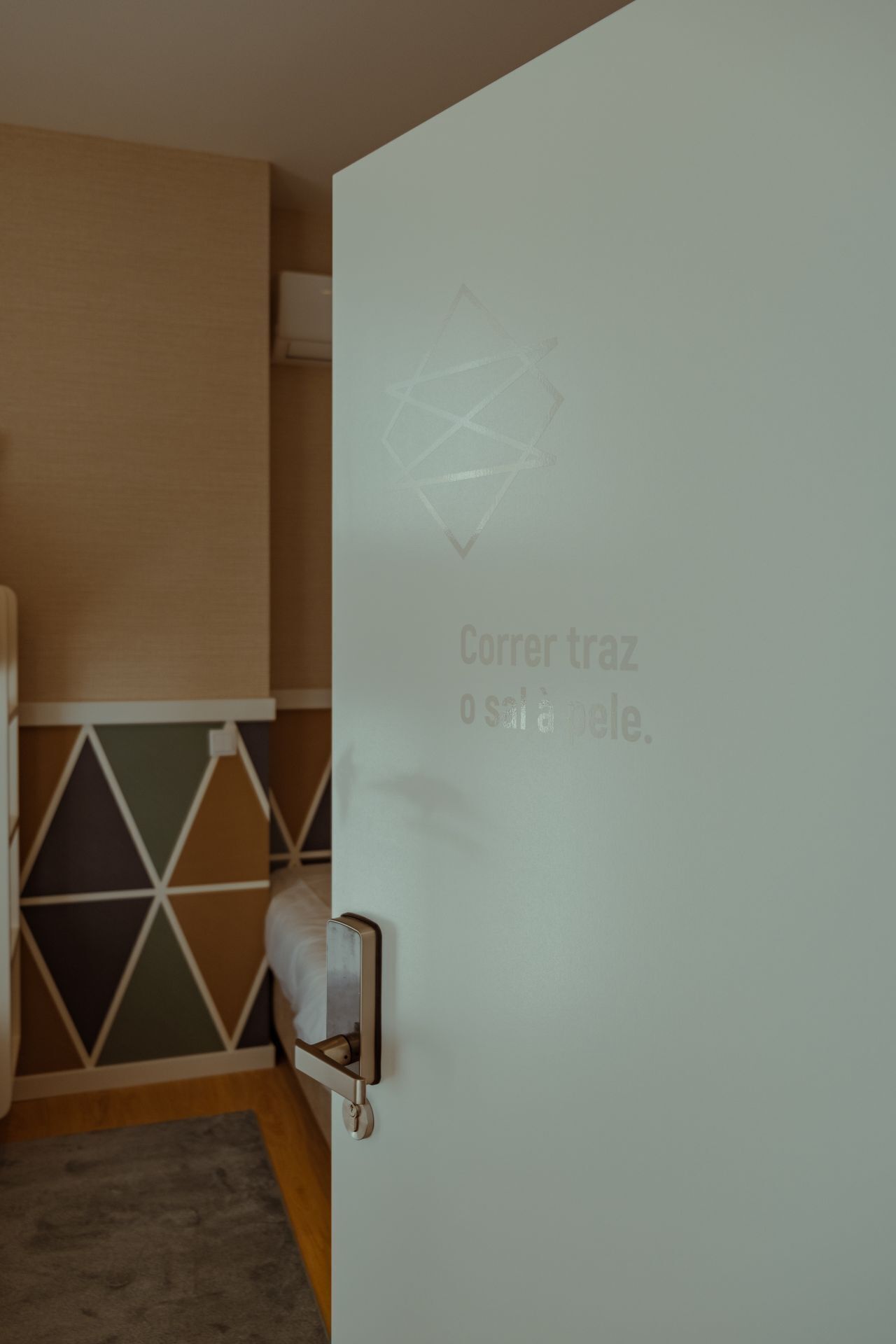 Habitación de hotel con una puerta de vidrio esmerilado que presenta un diseño geométrico y el texto 