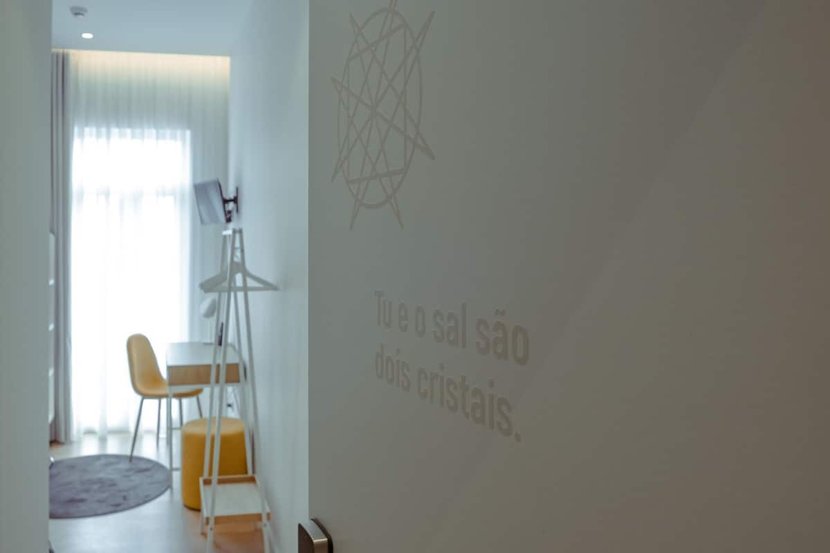 Ein modernes Zimmer mit Projektionsschirm, der Text zeigt, einer Tafel mit geometrischem Design und einem Essbereich mit Stühlen und Tisch.
