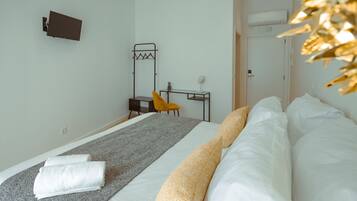 Una habitación de hotel con cama, escritorio, silla y perchero.