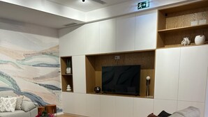 A modern living room with a grey sofa, a glass coffee table, and a flat-screen TV mounted on a wooden shelf. - Pedra de Sal Hostel & Suites (Rio Maior)