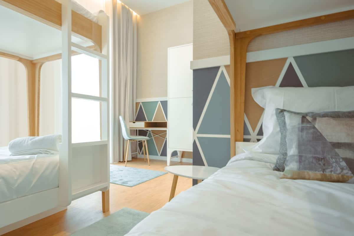 Ein modernes Hotelzimmer mit Stockbett, Schreibtisch und einer gemütlichen Sitzecke.