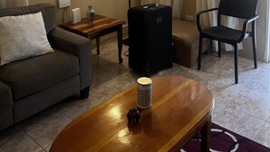 A living room with a sofa, a table, a chair, a suitcase, and a lamp. - Prime Negril Location - 2br brand new apartment. New Water tank installed. (Negril)
