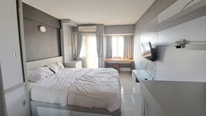 Ein modernes Hotelzimmer mit einem großen Bett, einem Schreibtisch und einem an der Wand montierten Fernseher.