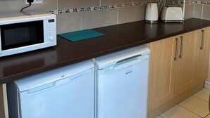 Eine kompakte Küche mit Holzausstattung, einer Mikrowelle, einem Toaster und einem Geschirrspüler.