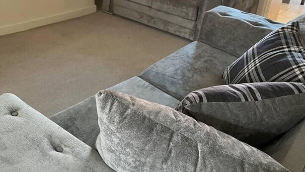 Ein Wohnzimmer mit grauem Sofa und Fenster mit Blick.
