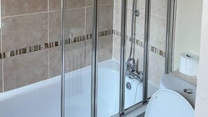 Eine Duschkabine mit Badewanne und Toilette im angrenzenden Raum.