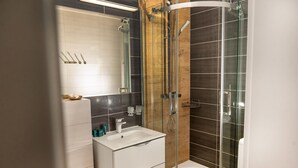 Une salle de bain moderne avec une douche à parois de verre, un lavabo blanc et un grand miroir.