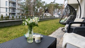 Une terrasse avec une table dressée pour deux personnes, agrémentée d’un vase de fleurs et d’une bougie.