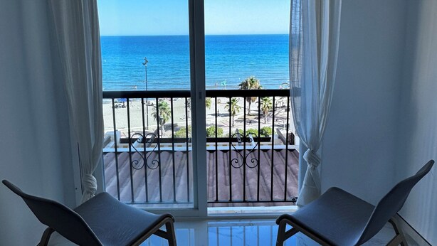 A balcony with two chairs, a view of the beach, and a clear blue sky. - Beautiful Place With Endless sea View (Fuengirola)