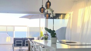 A modern kitchen with a white countertop, hanging pendant lights, and a view of the sea. - Beautiful Place With Endless sea View (Fuengirola)