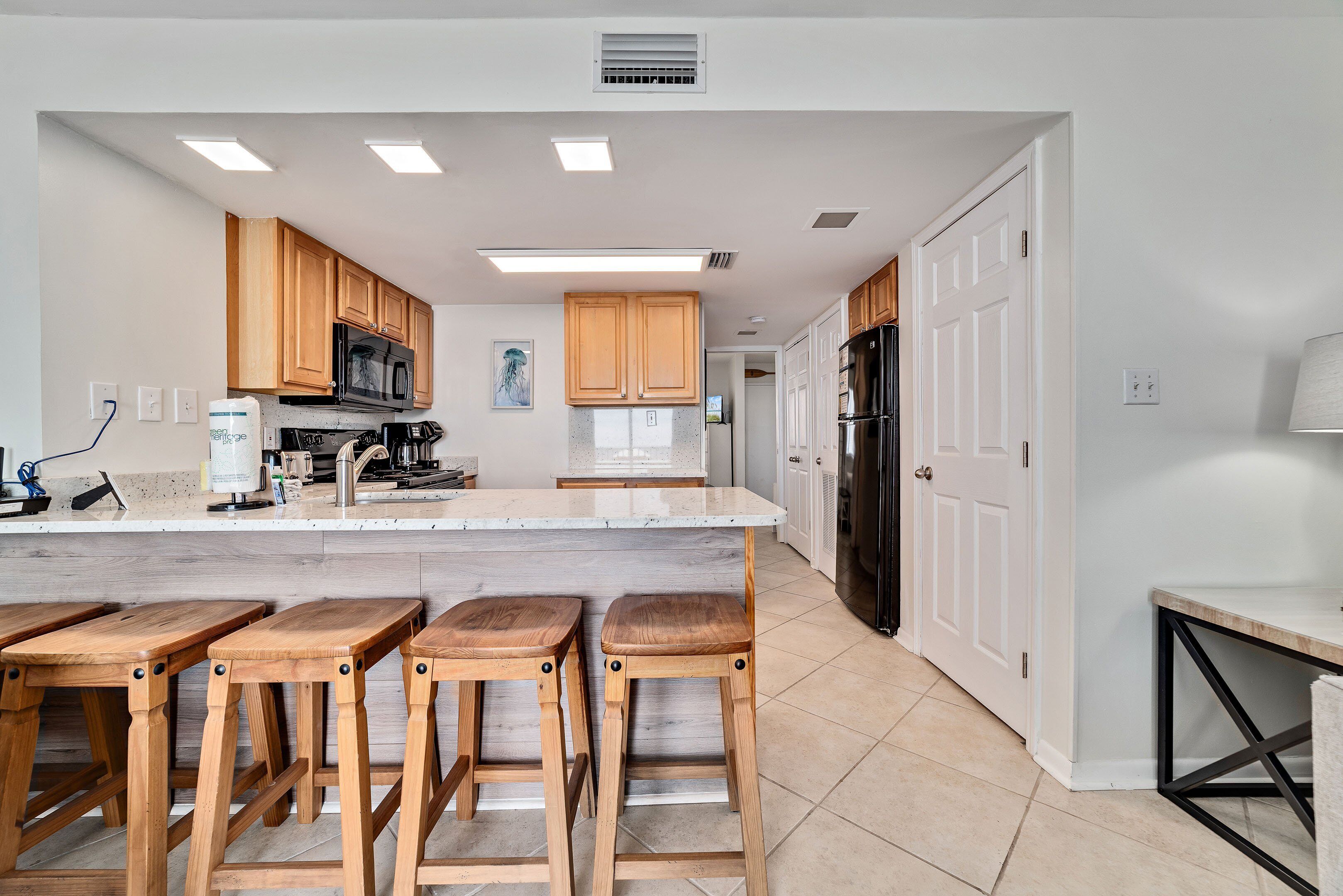 Una cocina moderna con armarios de madera, encimera de mármol y una isla central con taburetes.