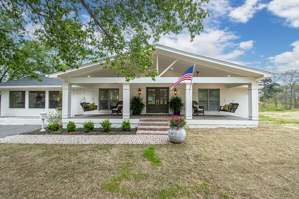 A two-story house with a covered porch, a brick pathway, and a flag. - The Legacy at DeGray (Bismarck)