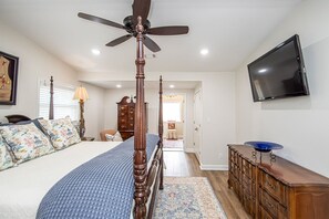 A bedroom with a four-poster bed, a ceiling fan, a flat-screen TV, and a wooden dresser. - The Legacy at DeGray (Bismarck)