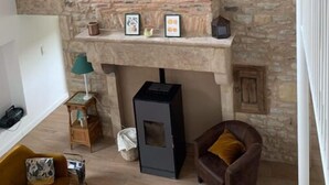 Una habitación con pared de piedra, chimenea, sofá y sillón.