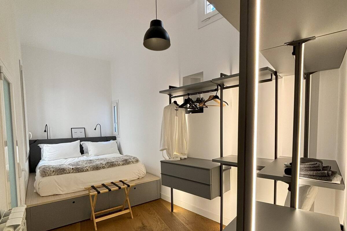 A modern bedroom with a bed, bedside table, and a hanging light fixture.