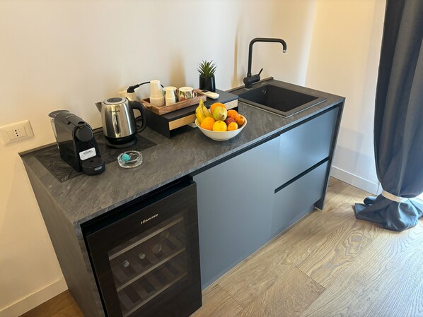 Une cuisine moderne équipée d’un lave-vaisselle encastré, d’une machine à café, d’un panier à fruits et d’un évier.