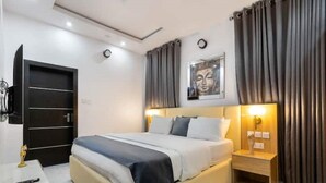 A modern hotel room with a bed, bedside table, and a wall-mounted picture.