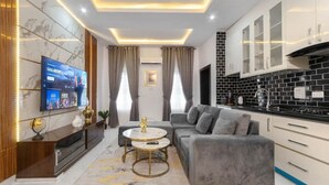 A modern living room with a grey sofa, a coffee table, and a TV mounted on the wall.