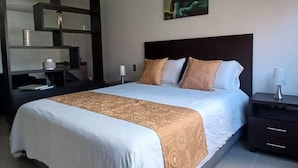 Quarto de hotel bem arrumado com uma cama grande, mesa de cabeceira, espelho e um quadro na parede.