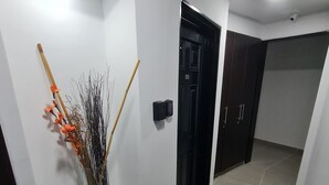 Um corredor com parede branca, porta com moldura preta e luminária de embutir no teto.