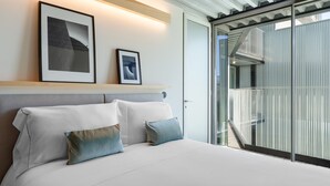 A modern hotel room with a large bed, a headboard, and a balcony with a glass door. - Feel Porto Matosinhos City Flat IV (Matosinhos)