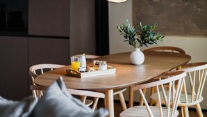 A wooden dining table with a tray of breakfast items, a potted plant, and a hanging light fixture. - Feel Porto Matosinhos City Flat IV (Matosinhos)