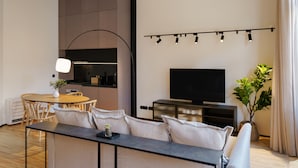 A modern living room with a sofa, a dining table, and a TV. - Feel Porto Matosinhos City Flat III (Matosinhos)