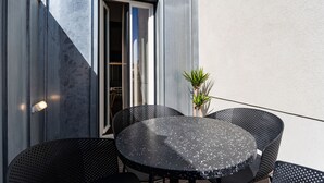 A round table with four chairs, a potted plant, and a door with a window. - Feel Porto Matosinhos City Flat V (Matosinhos)