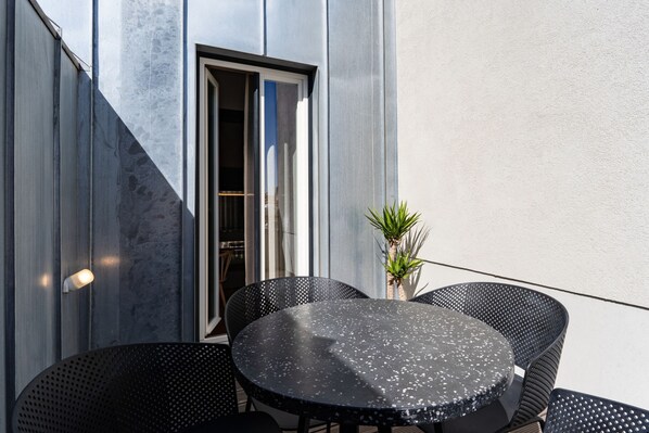 A round table with four chairs, a potted plant, and a door with a window. - Feel Porto Matosinhos City Flat V (Matosinhos)