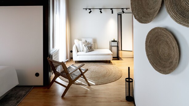 A modern living room with a white sofa, a woven rug, and a wooden floor. - Feel Porto Matosinhos City Flat V (Matosinhos)