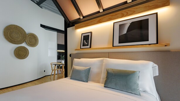 A modern bedroom with a large bed, a headboard, and a wall-mounted shelf with framed pictures. - Feel Porto Matosinhos City Flat V (Matosinhos)